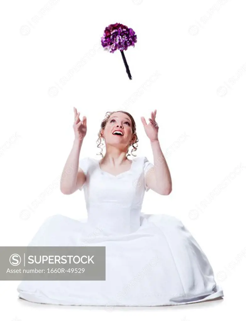 Happy bride throwing bouquet, studio shot