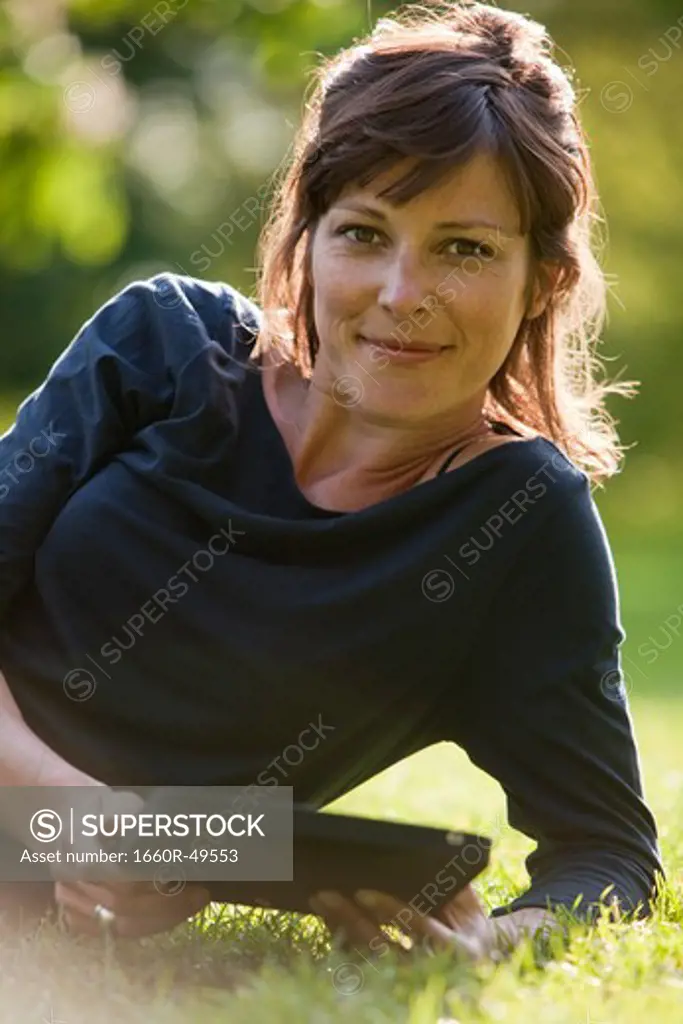 UK, London, Portrait of young woman sitting in park and using digital tablet