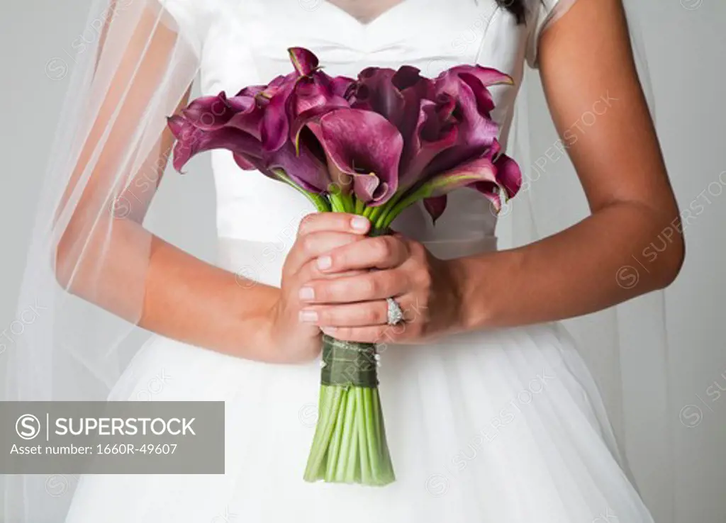 Mid section of bride holding bouquet