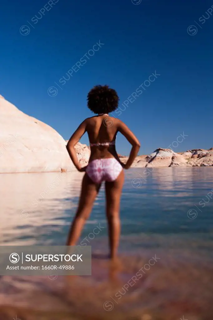 Woman standing in shallow water on rocky beach