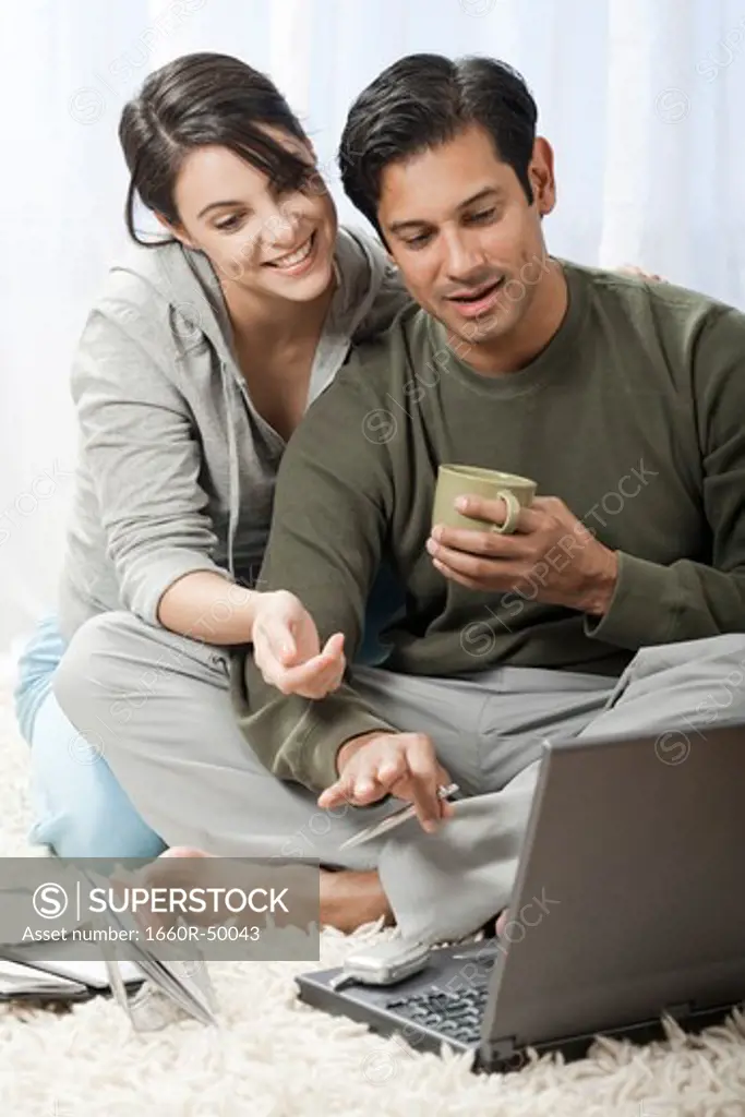 Man and woman on carpet with laptops