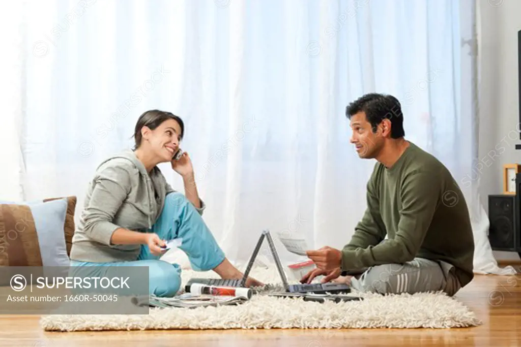 Man and woman on carpet with laptops