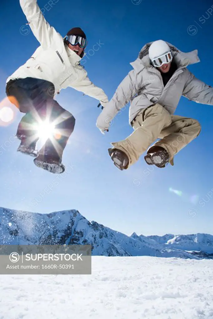 Two friends jumping outside in the snow