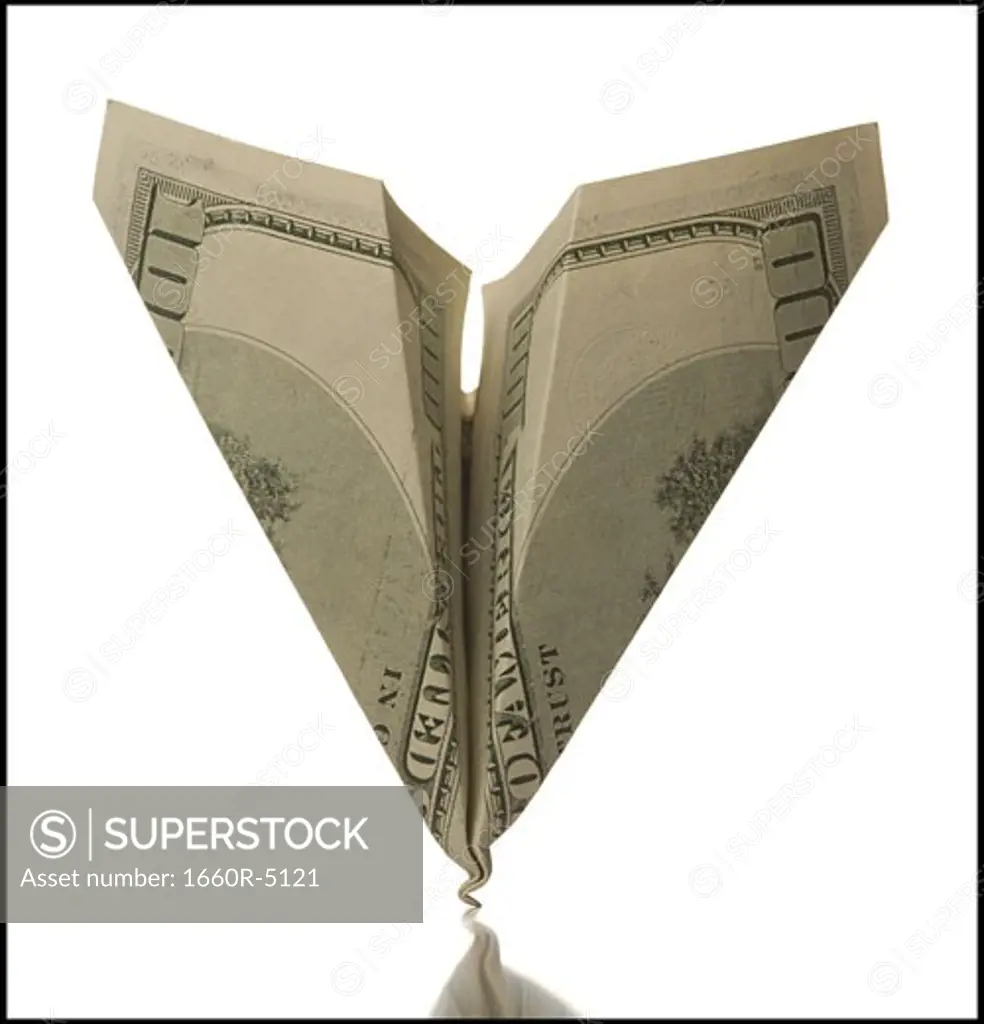 Close-up of a paper airplane made from one hundred dollar bill with damaged nose