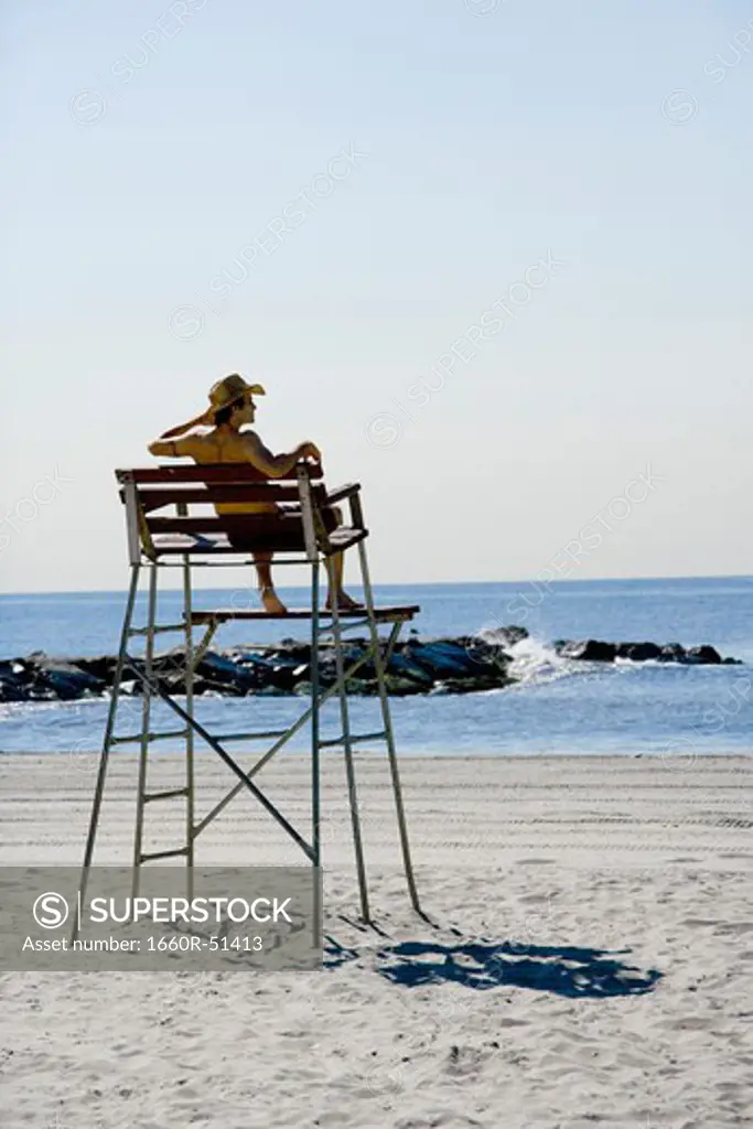 Man sitting in lifeguard chair at beach
