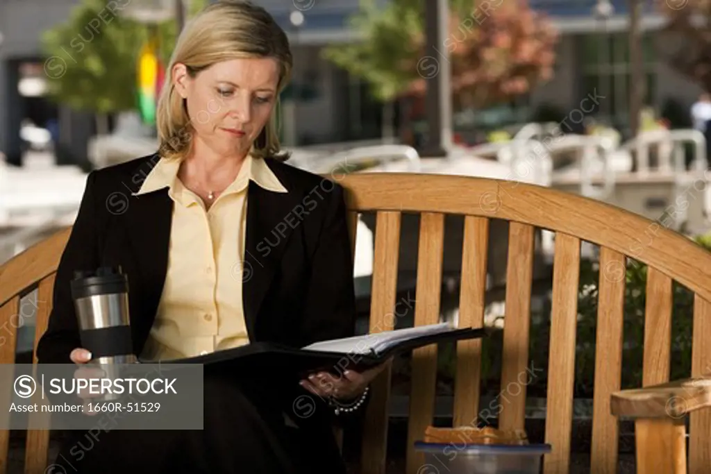 Businesswoman reading on park bench