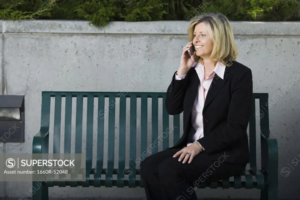 Businesswoman on cellular sitting on a bench