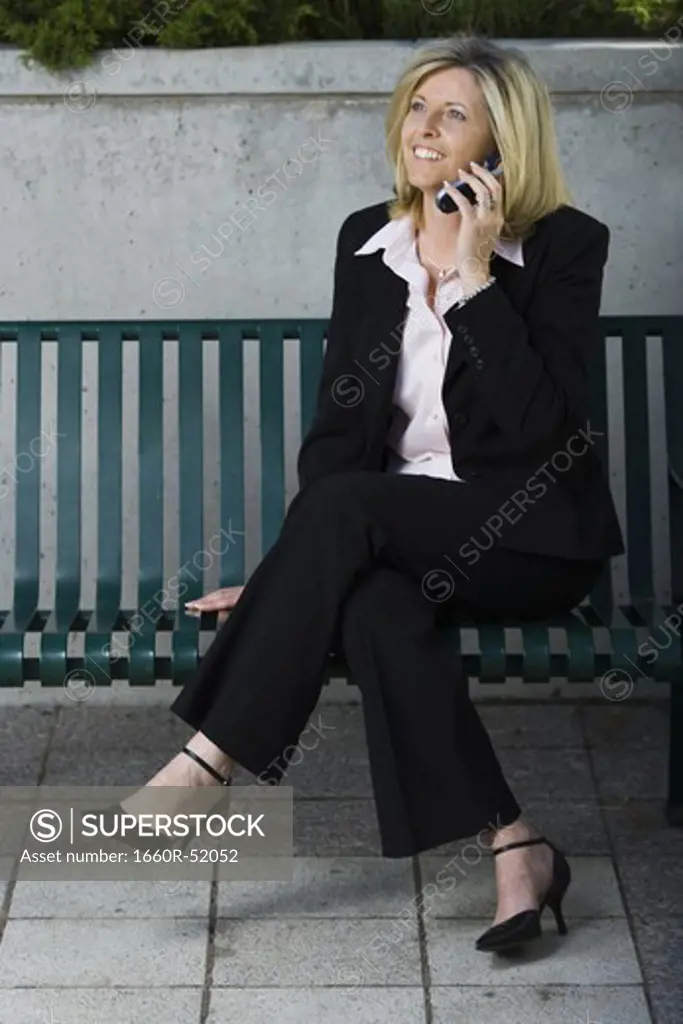 Businesswoman on cellular sitting on a bench