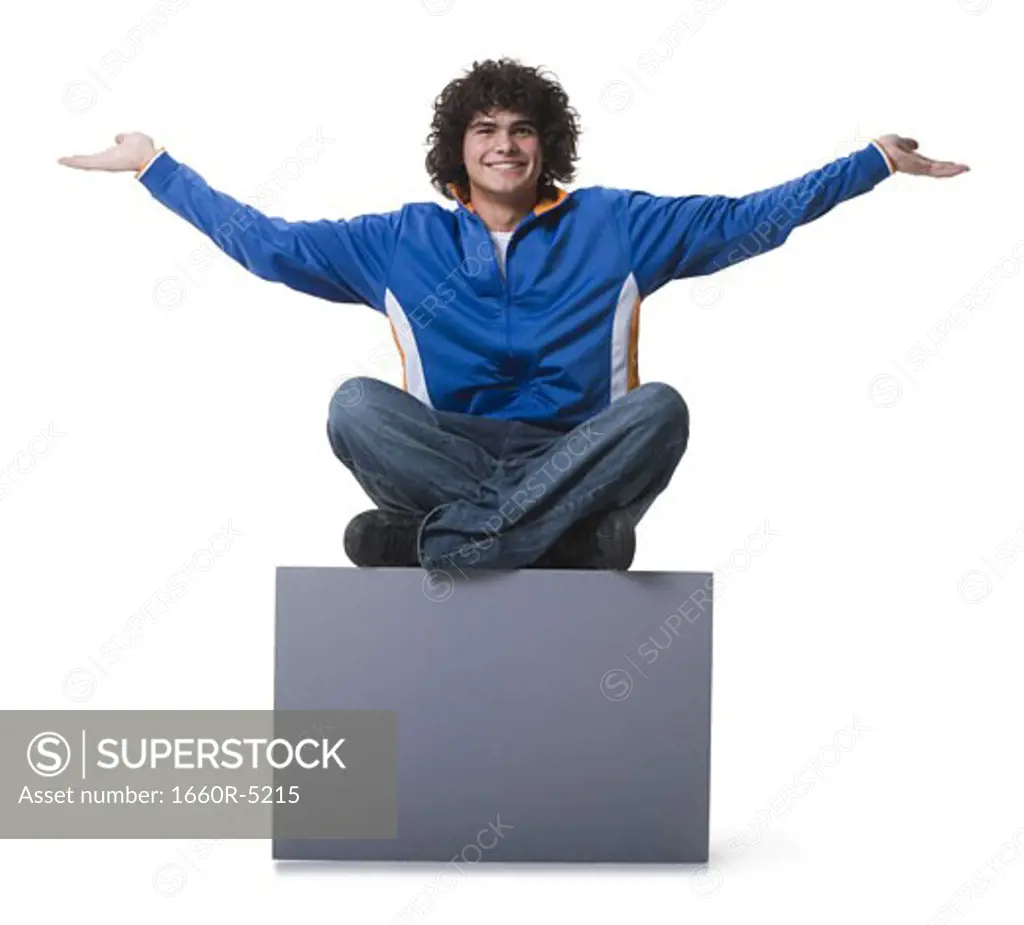 Portrait of a teenage boy sitting on a blank sign