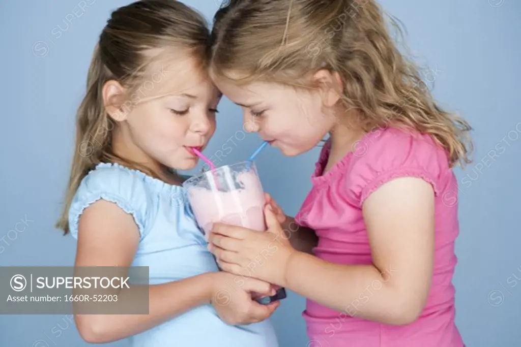 Two girls sharing a milkshake