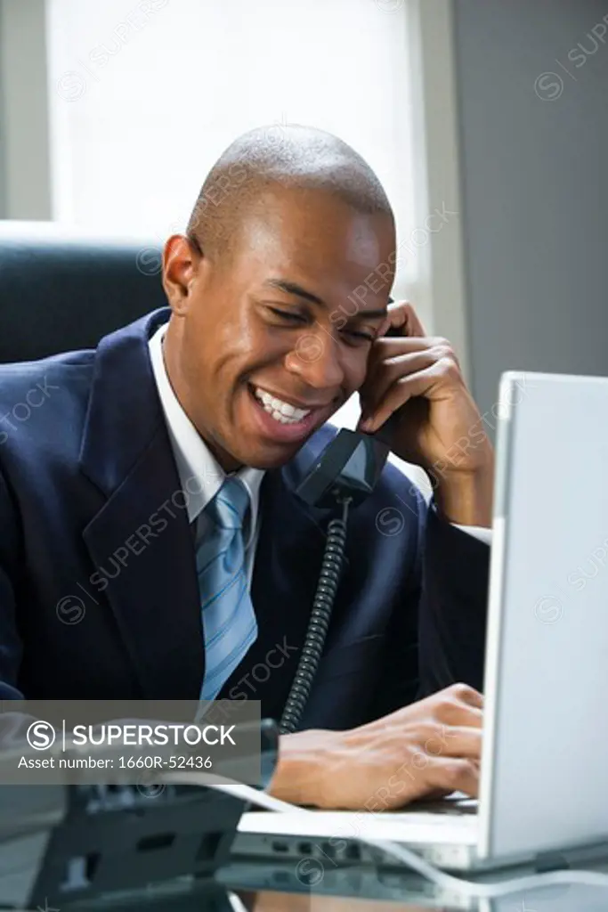 Businessman on laptop and on the phone