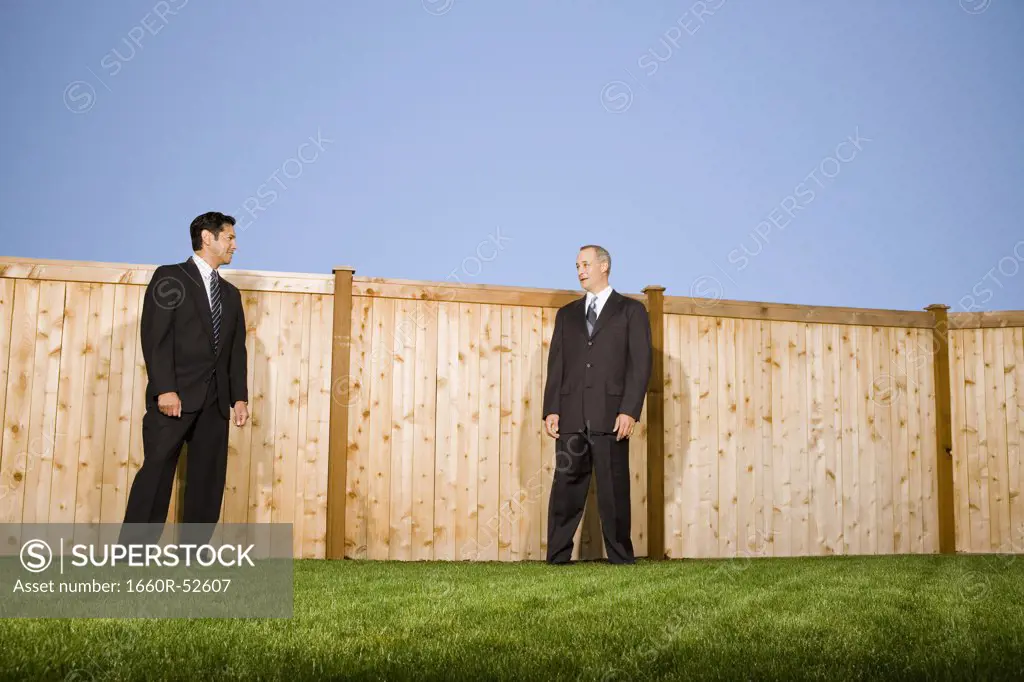 Businessmen standing in front of a wooden fence