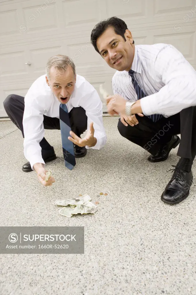 Two businessmen gambling on a driveway
