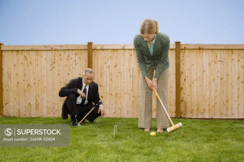 Two businesspeople playing croquet