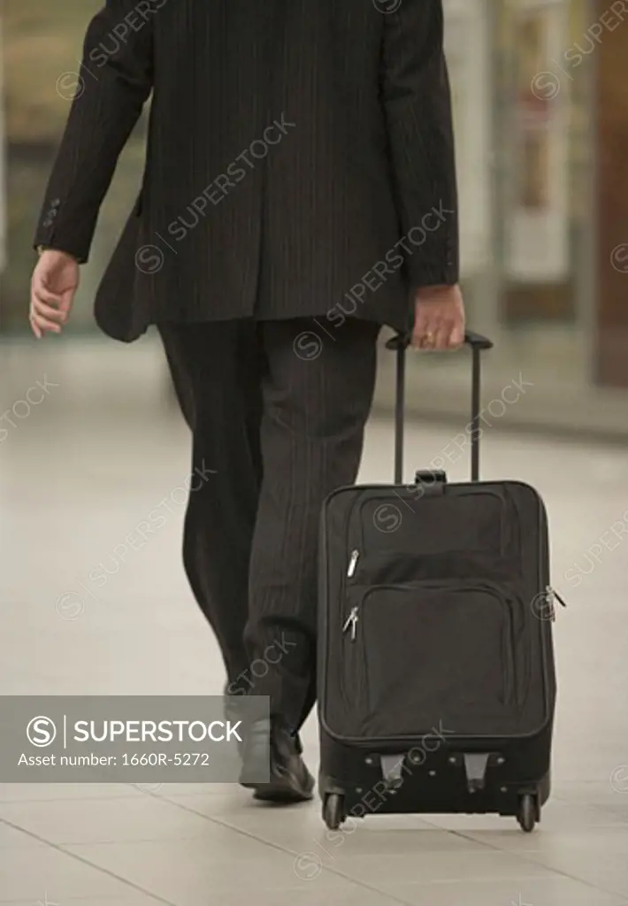 Rear view of a man pulling a suitcase
