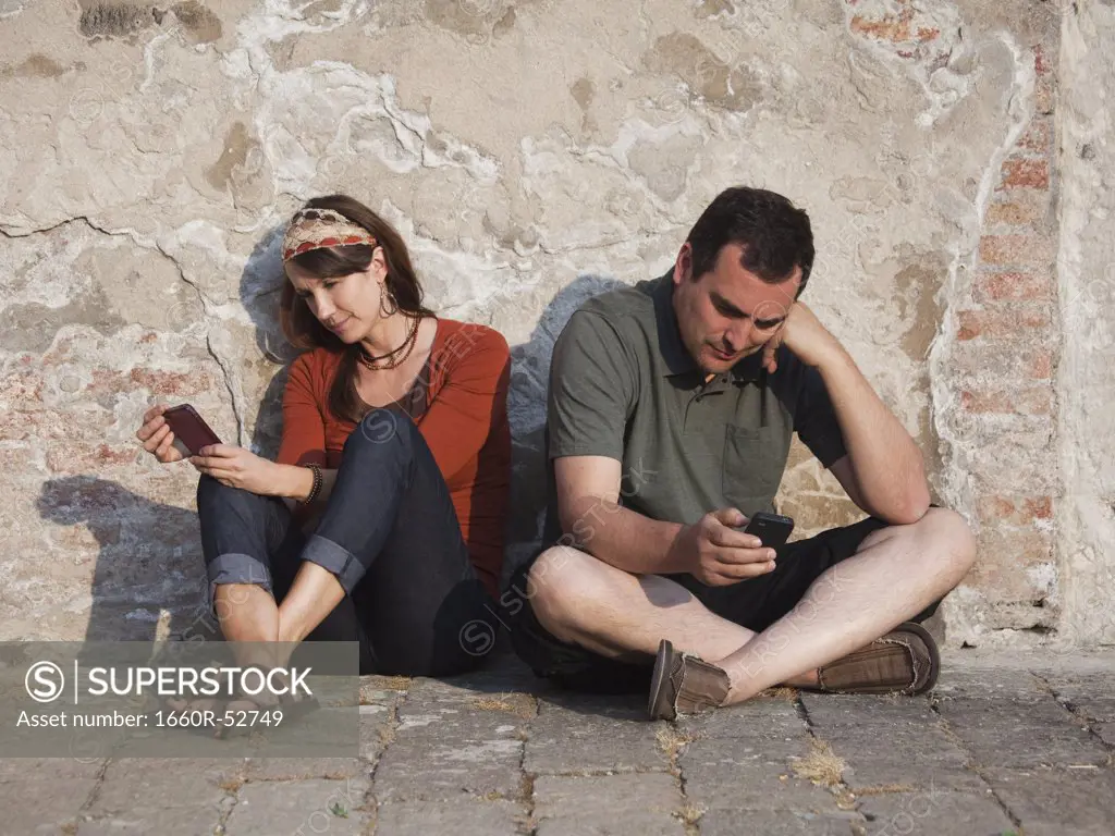 Italy, Venice, Couple text messaging by wall