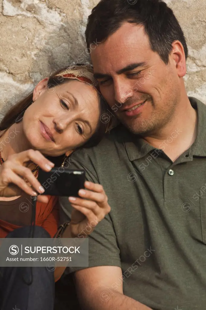 Italy, Venice, Couple viewing digital camera by wall