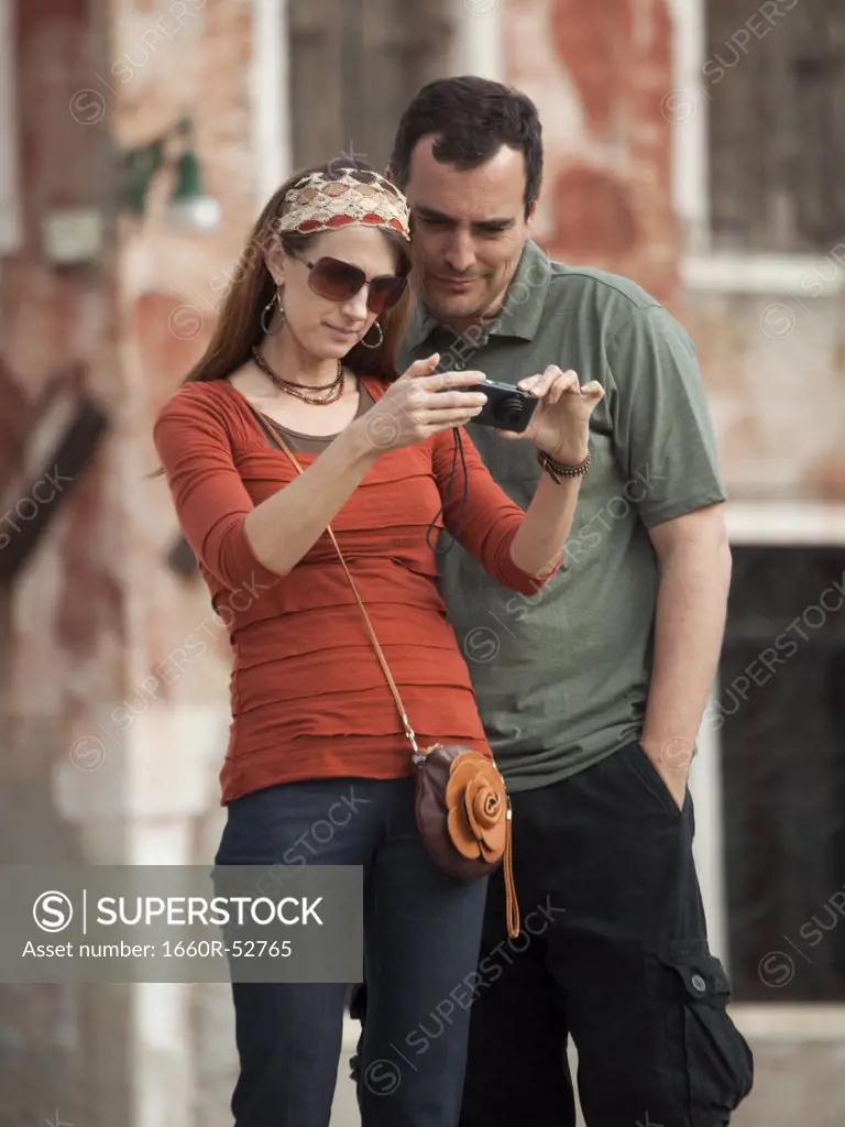 Italy, Venice, Couple viewing digital camera in city