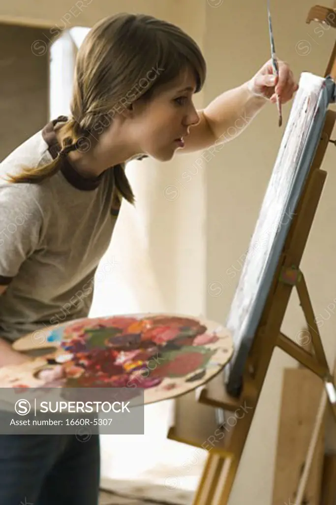 Profile of a young woman painting on a canvas