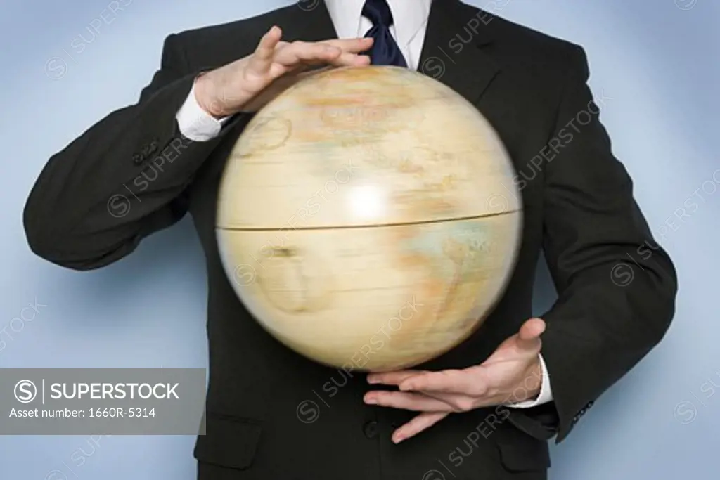 Mid section view of a businessman holding a spinning globe