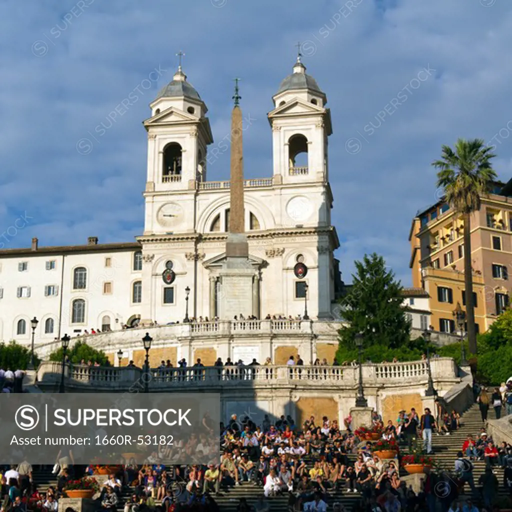 Italy, Rome, Tourists on Spanish Steps at sunset, church of the Santissima Trinita dei Monti in background