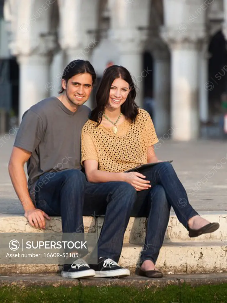 Italy, Venice, Portrait of young couple sitting on steps on St. Mark's Square