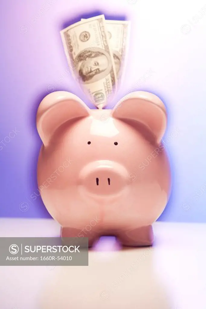 Pink piggy bank with dollar bills
