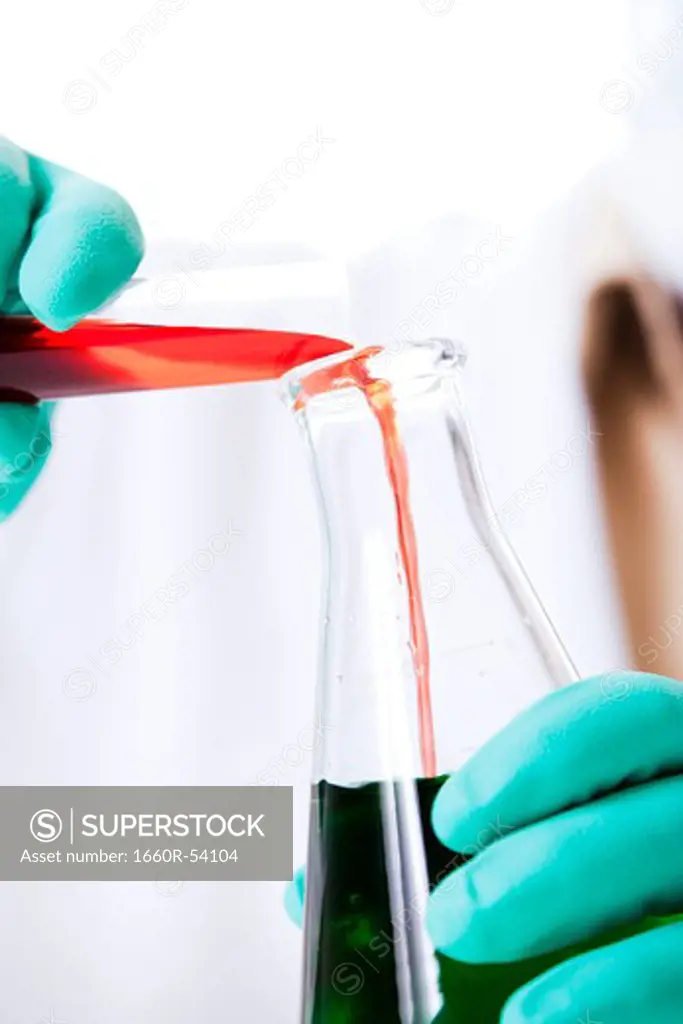 Closeup of scientist pouring chemicals into beaker