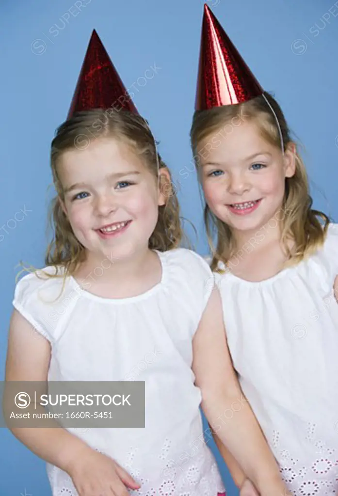 Portrait of two sisters wearing birthday hats and smiling