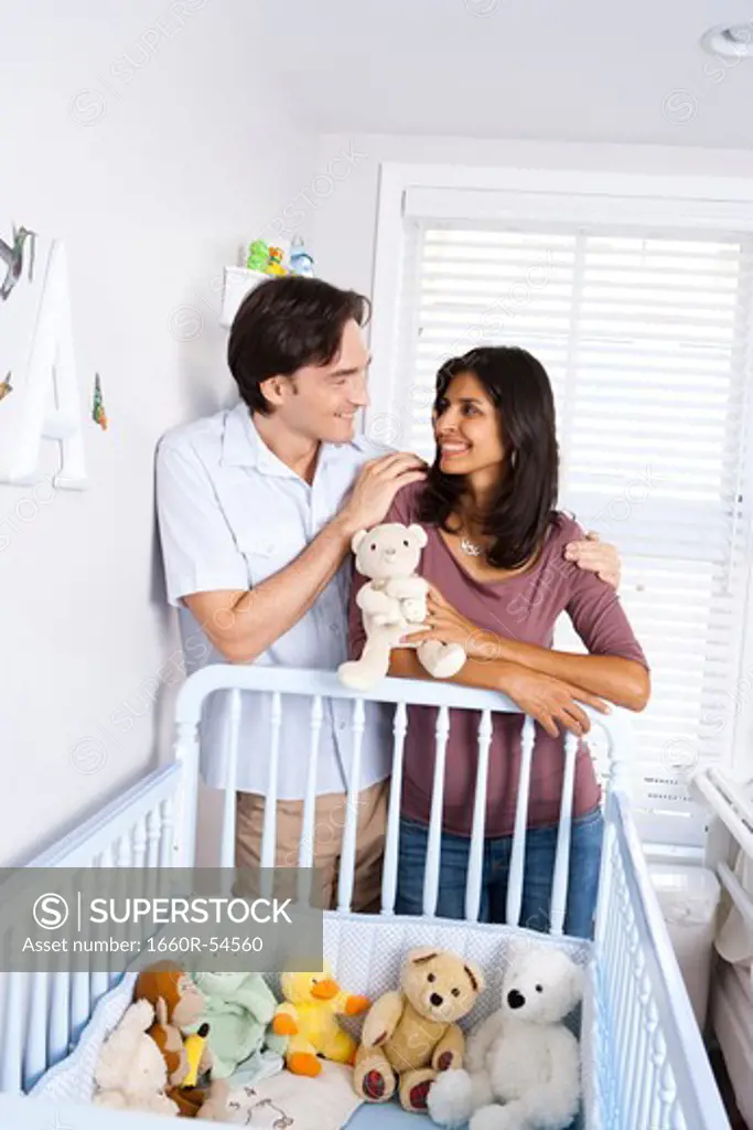 Married couple leaning on baby crib