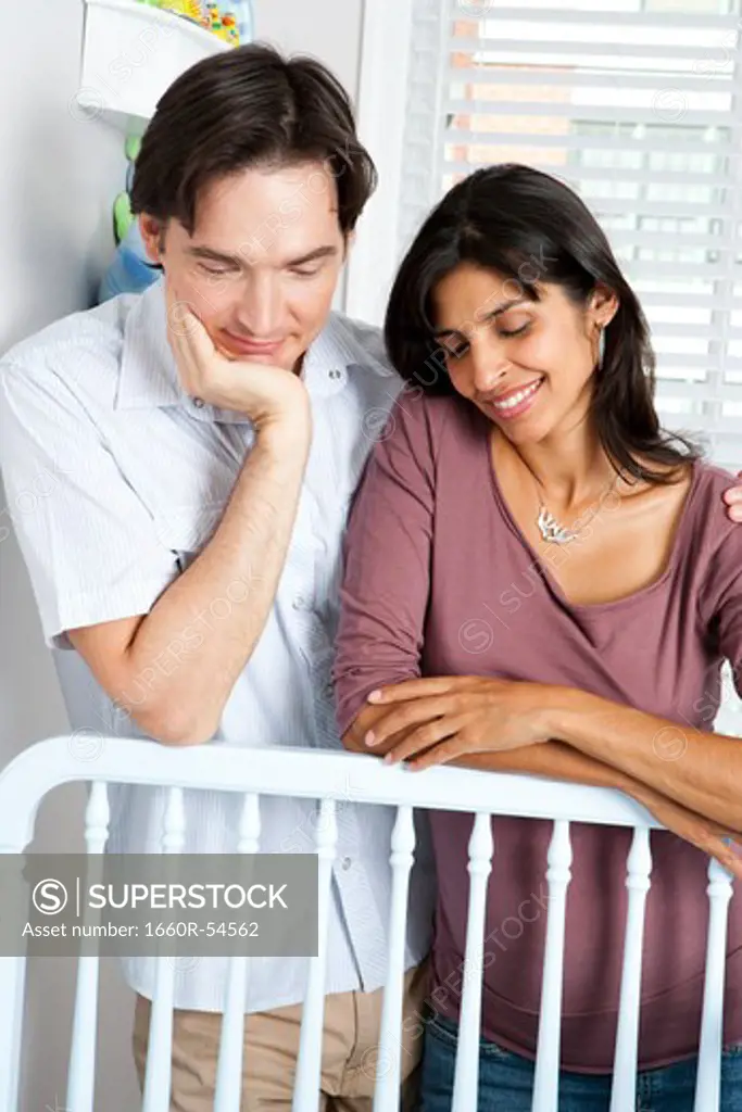 Married couple leaning on baby crib