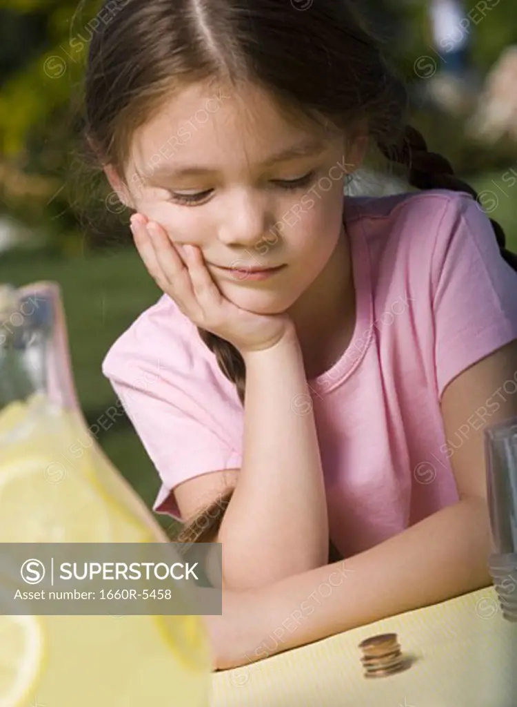Close-up of a girl looking at a stack of coins and thinking