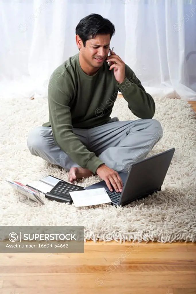 Man with laptop talking on phone