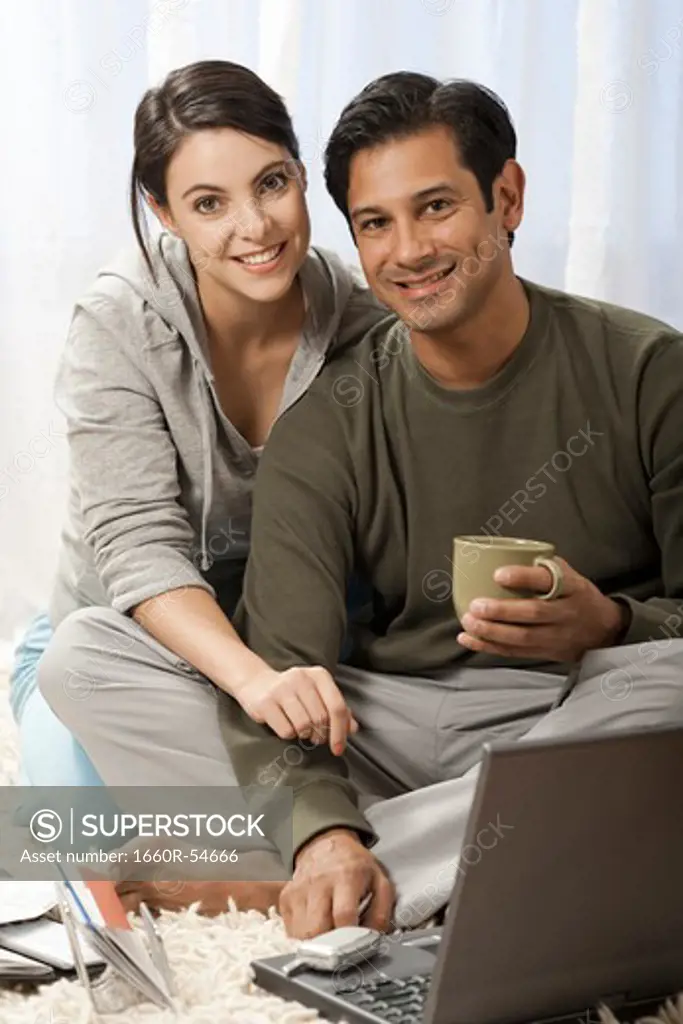 Man and woman on carpet with laptop