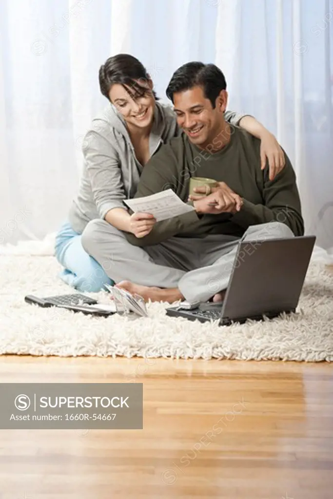 Man and woman on carpet with laptop