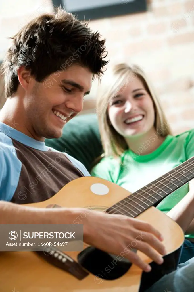 Man singing with guitar for woman