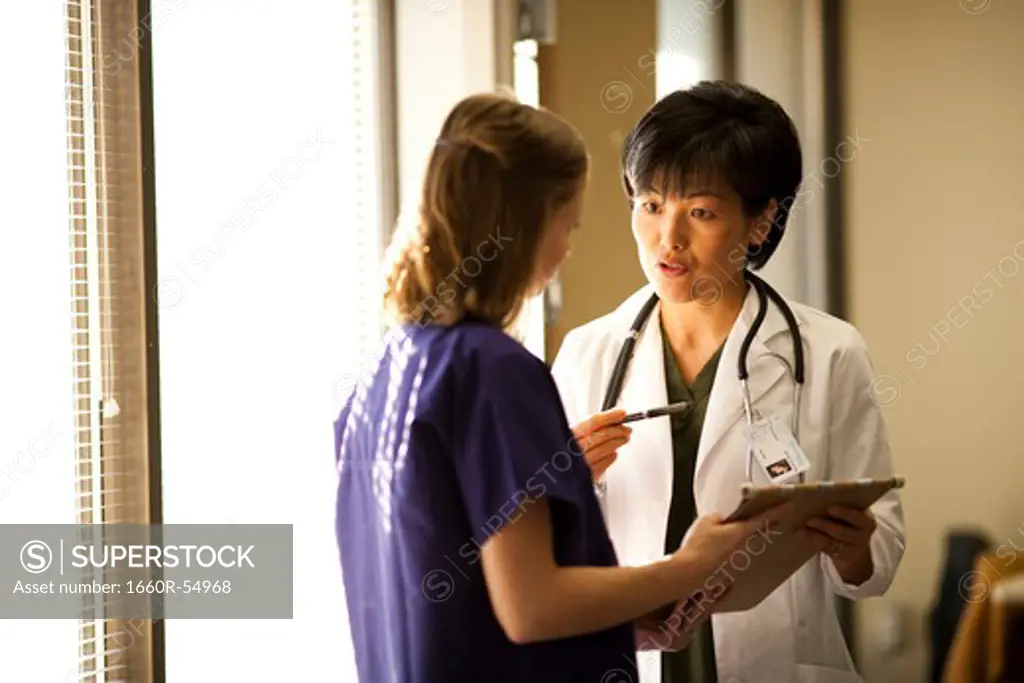 Female doctor explaining patient records to nurse