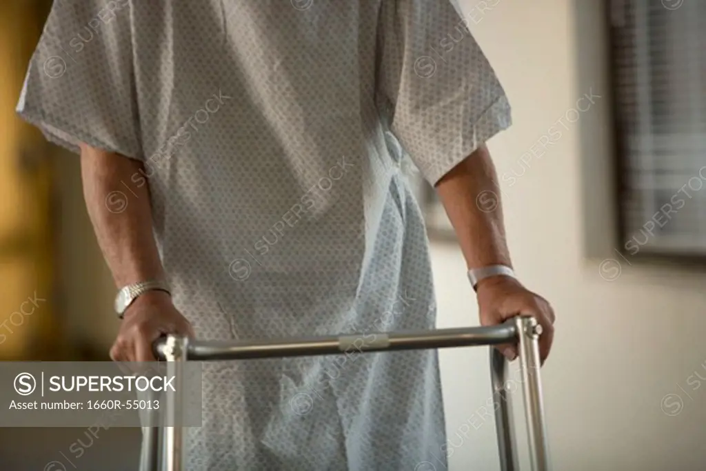 Mature man in hospital gown with walker