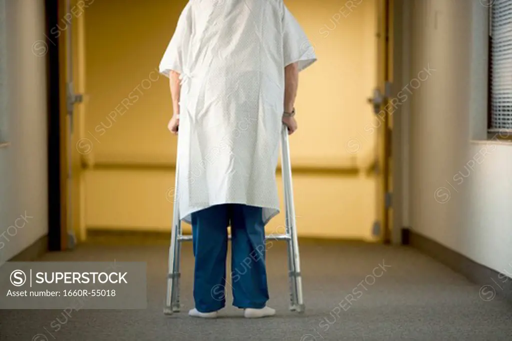 Mature man in hospital gown with walker