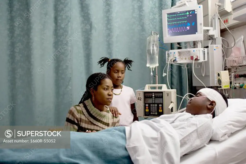 Family watching boy in hospital bed with head bandages