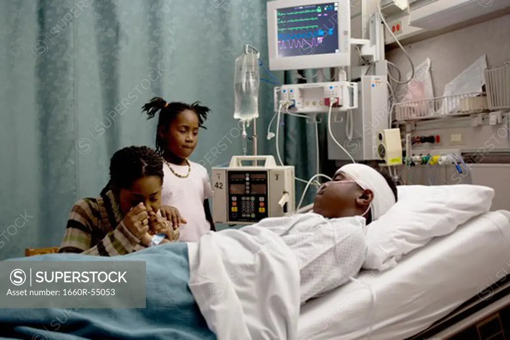 Family watching boy in hospital bed with head bandages