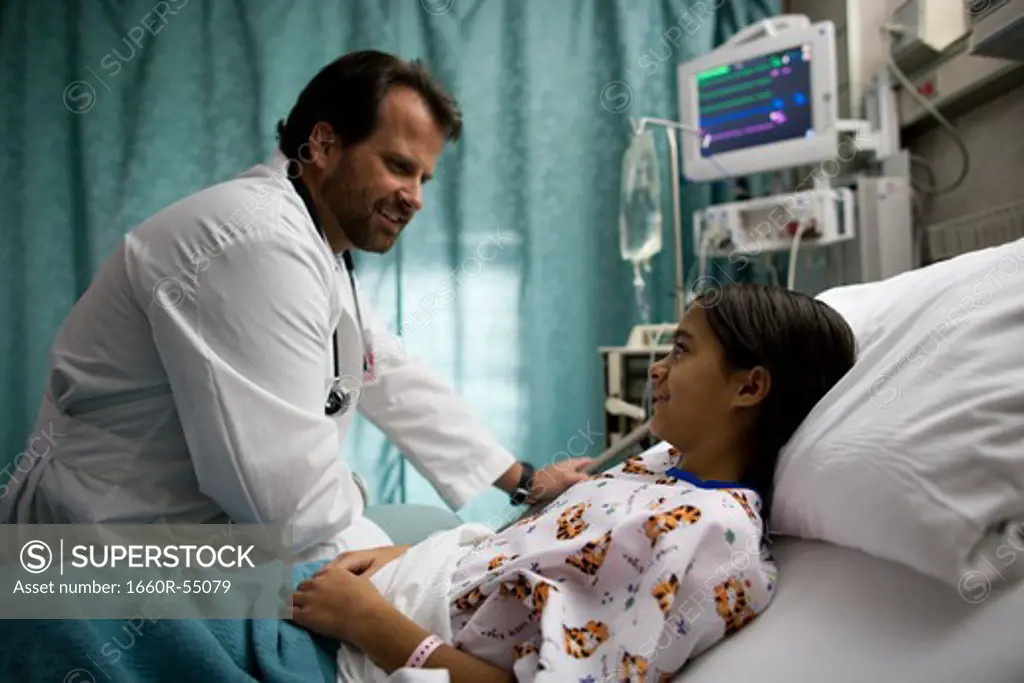 Doctor examining girl in hospital bed