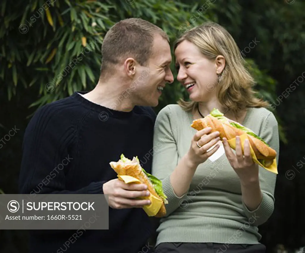 Close-up of a young couple holding sandwiches