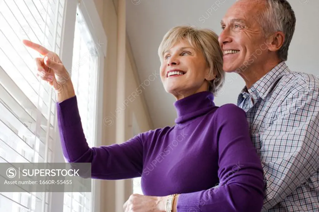 Mature couple looking through blinds