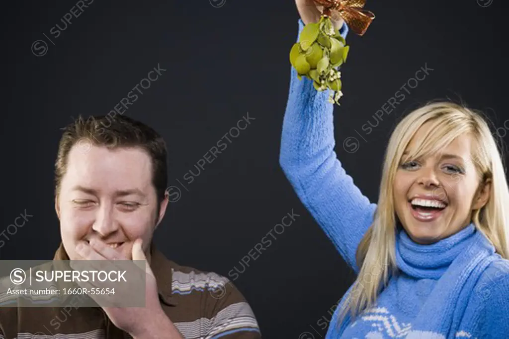Woman with mistletoe giving man kiss