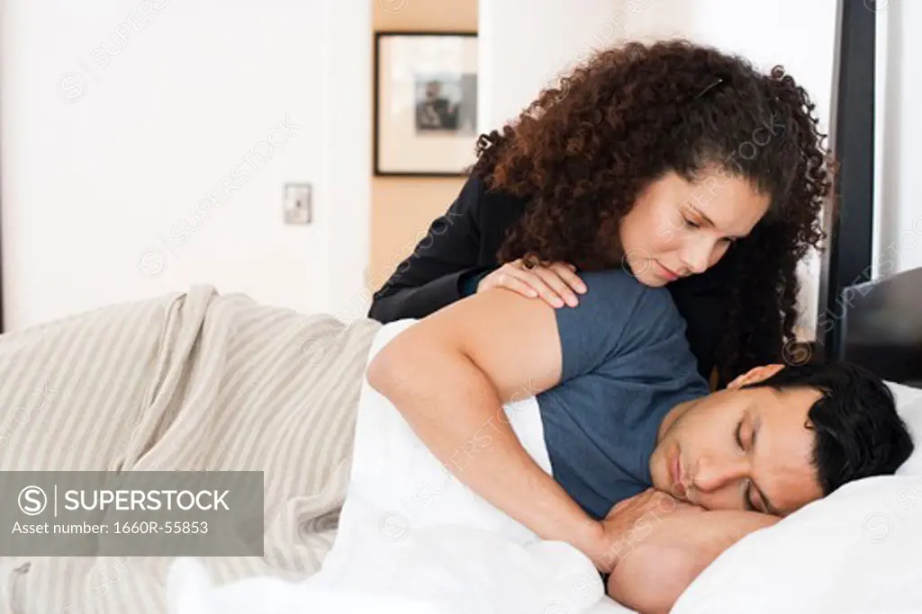 Woman watching man sleeping in bed