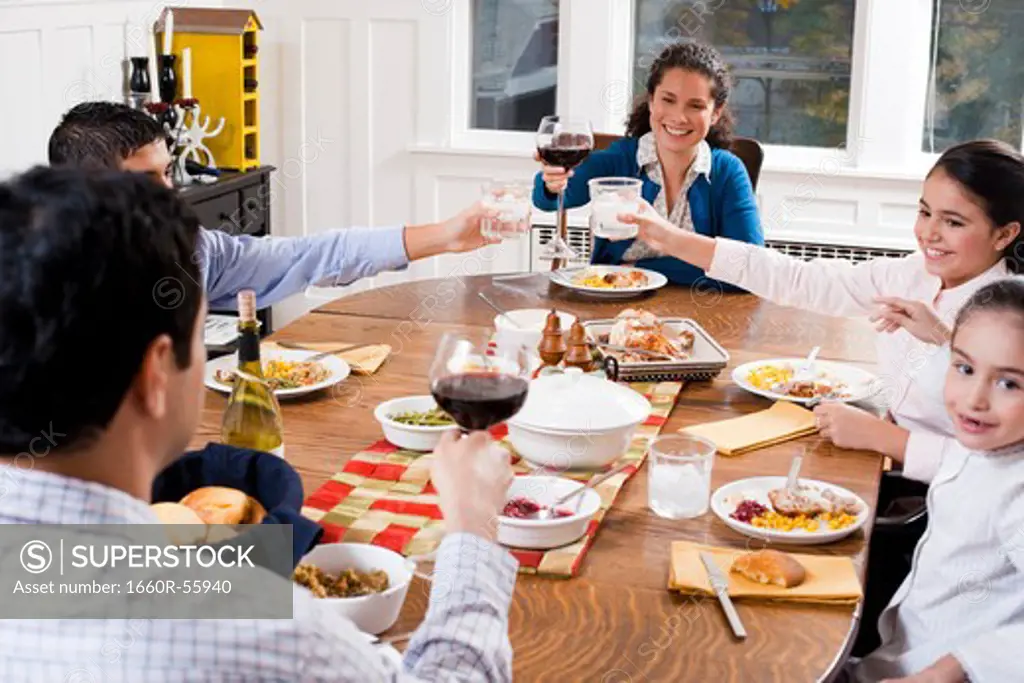 Family at dinner table toasting