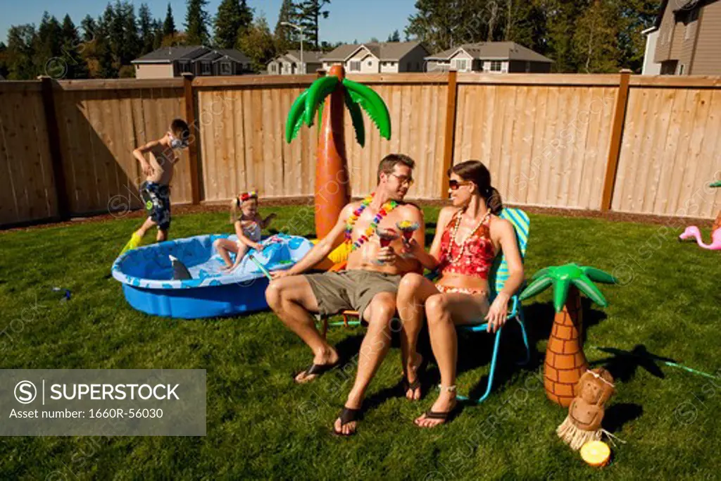 Family in yard with children's pool and cocktails