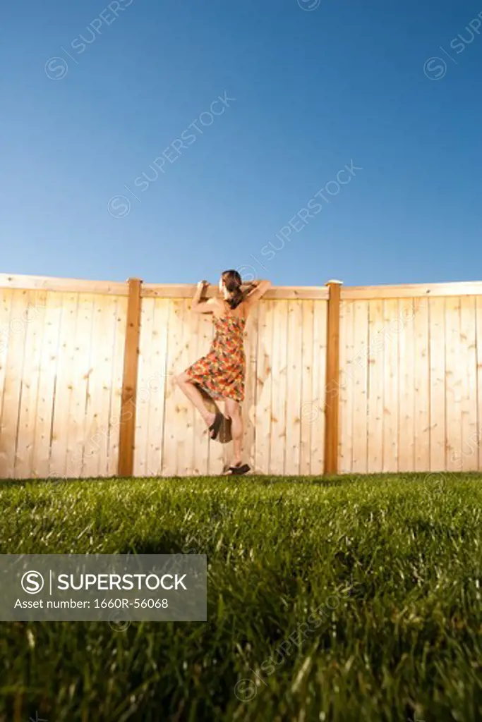Woman peeping over wooden fence