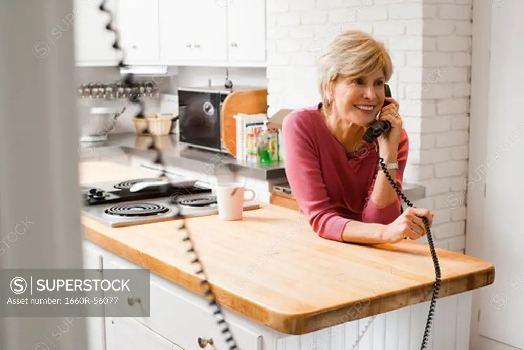 Mature woman talking on telephone in kitchen